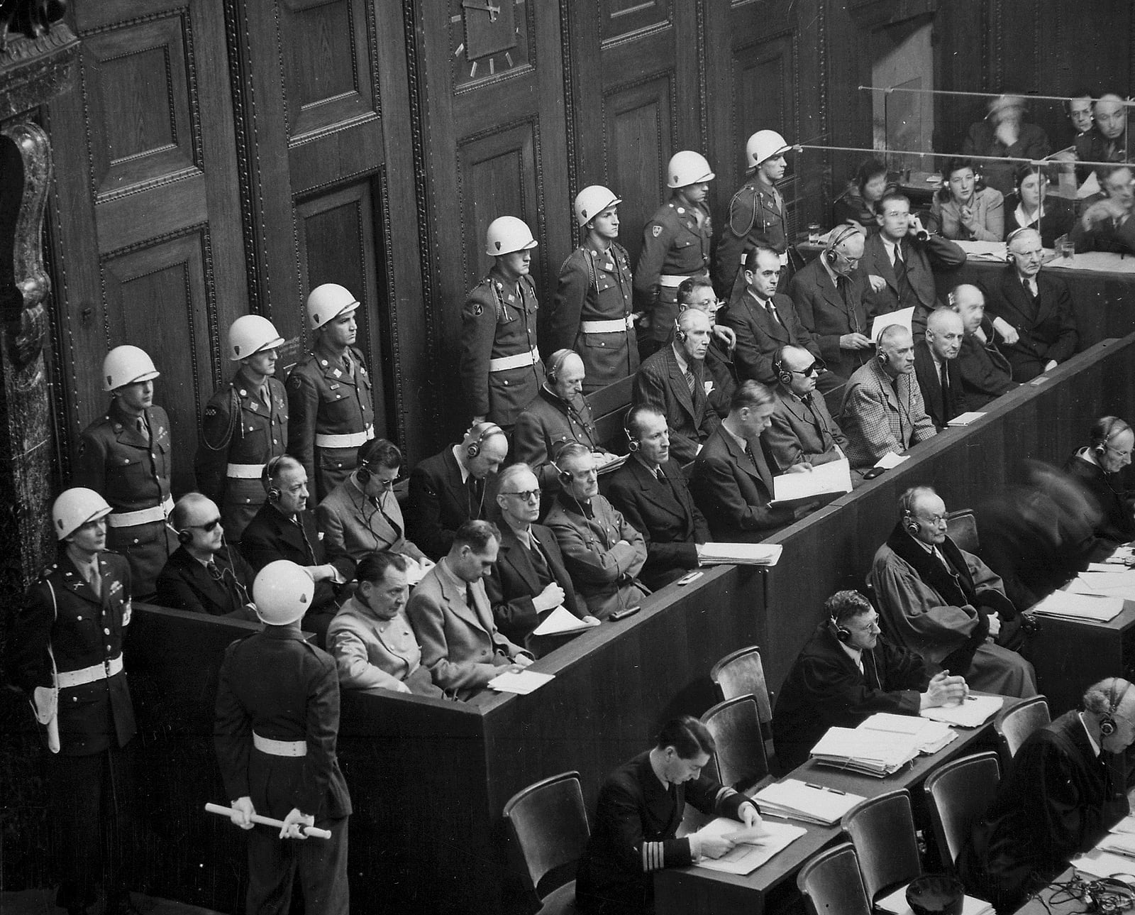 The defendants' dock at the Nuremberg trial seen from above, with American military guards standing behind the accused