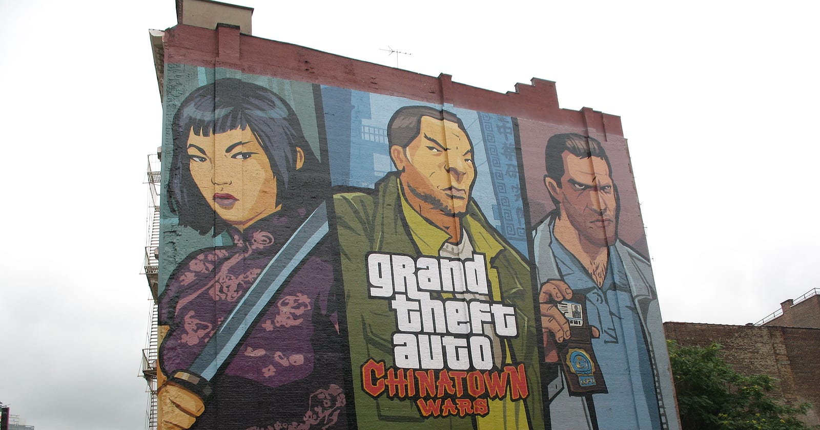 Un murale alto quanto un palazzo con tre personaggi disegnati e la scritta Grand Theft Auto Chinatown Wars